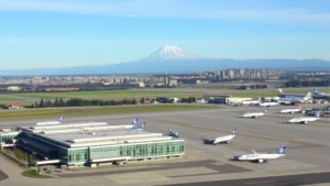 Aerial view of Seattle-Tacoma International Airport with Mount Rainier visible in the background, modern terminal buildings, aircraft on tarmac, clear day with blue sky
