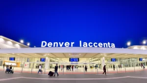 Denver International Airport terminal exterior with modern architecture, wide angle view showing check-in area and travelers with luggage, bright professional lighting, daytime