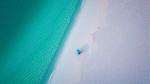 Aerial view of pristine white sand beaches in Gulf Shores Alabama with turquoise water and beach umbrellas, sunrise lighting, photorealistic