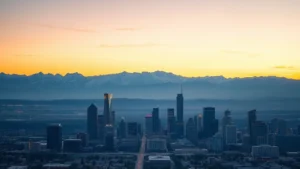 Aerial view of Denver skyline with Rocky Mountains in background at sunrise, snow-capped peaks visible, city lights fading, golden hour lighting, photorealistic landscape photography