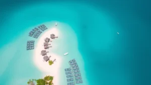 Aerial view of turquoise water with overwater bungalows and tropical island landscape, bright daylight, crystal clear shallow lagoon