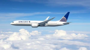 United Airlines Boeing 787 Dreamliner aircraft banking gracefully through blue sky with white clouds below during daytime flight