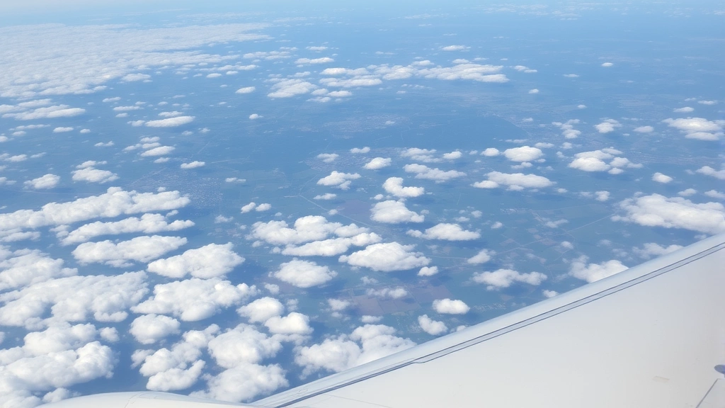 Aerial view of airplane flying over landscape between Chicago and Charlotte, scattered clouds below, wing visible in foreground, daytime flight