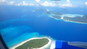 Aerial view of turquoise Caribbean waters surrounding St. Thomas, US Virgin Islands with white sand beaches and palm trees lining the coastline, shot from airplane window during approach to Cyril E. King Airport