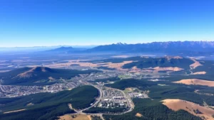 Aerial view of Bend Oregon surrounded by Cascade Mountains and forested landscape with clear blue sky, showcasing the destination beauty from above