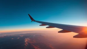 Modern aircraft in flight over Colorado mountains at sunrise, clear blue sky, wing visible in frame, dramatic landscape below, photorealistic high-quality image