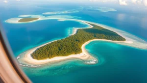 Aerial view of turquoise Caribbean waters surrounding Roatan island with white sandy beaches and lush green vegetation, shot from airplane window at sunrise